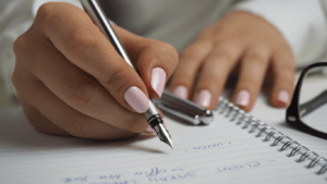 Write to win - Copywriting Kurs, Frau schreibt mit ihrem Füller ihre neuen Marketing Texte die verkaufen
